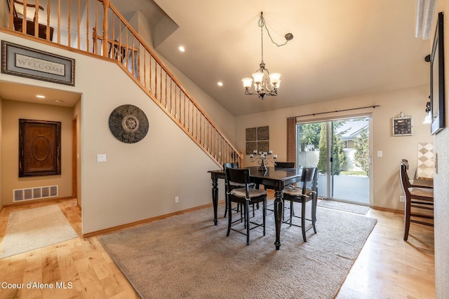 dining area with a high ceiling, a chandelier, and light hardwood / wood-style flooring