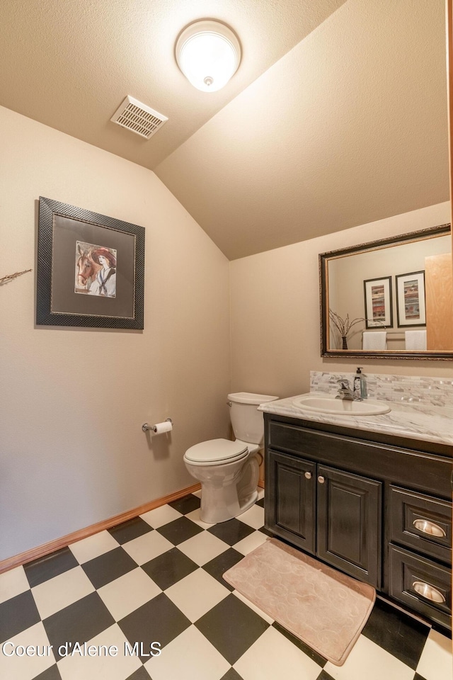 bathroom featuring lofted ceiling, toilet, vanity, and a textured ceiling