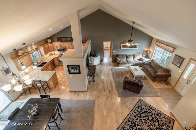 living room with sink, high vaulted ceiling, and light wood-type flooring