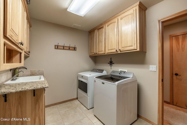 laundry room with light tile patterned flooring, cabinets, sink, and washer and dryer