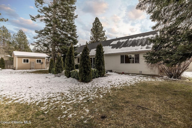 view of snowy exterior with a yard and an outbuilding