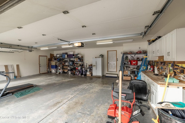 garage featuring a garage door opener, white refrigerator with ice dispenser, and a workshop area