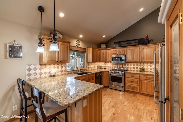 kitchen with sink, a breakfast bar area, high quality appliances, decorative light fixtures, and kitchen peninsula