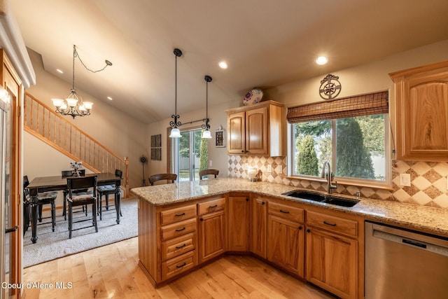 kitchen featuring hanging light fixtures, dishwasher, sink, and kitchen peninsula