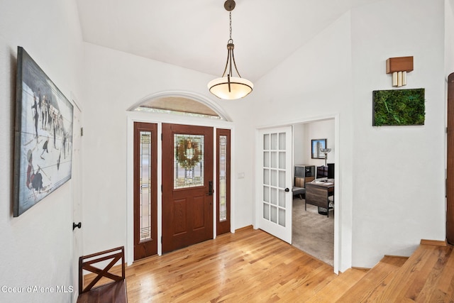 entrance foyer featuring wood-type flooring, high vaulted ceiling, and french doors