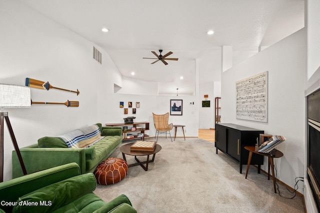 carpeted living room with ceiling fan and vaulted ceiling