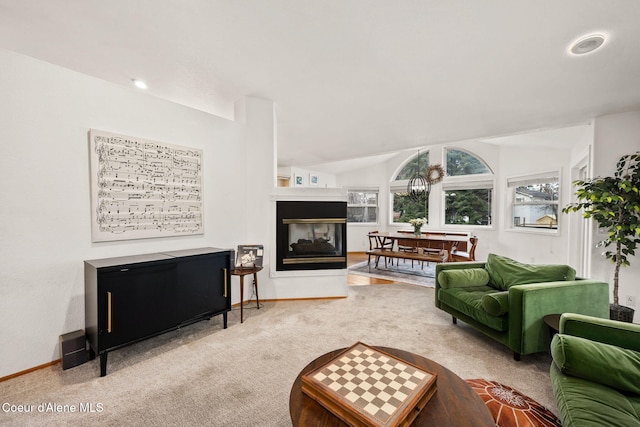 carpeted living room featuring a multi sided fireplace and vaulted ceiling