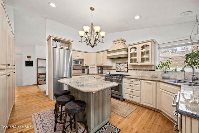 kitchen featuring premium range hood, a kitchen island, appliances with stainless steel finishes, tasteful backsplash, and sink