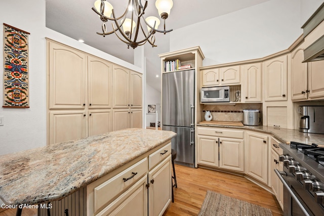 kitchen featuring light stone counters, built in appliances, decorative light fixtures, and light hardwood / wood-style floors