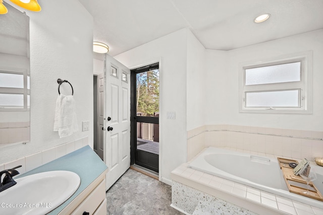 bathroom featuring tiled tub and vanity