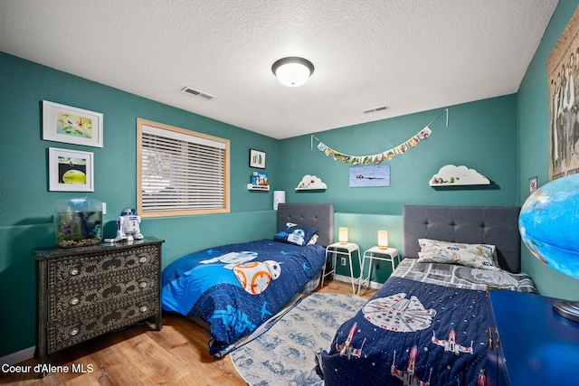 bedroom featuring hardwood / wood-style flooring and a textured ceiling