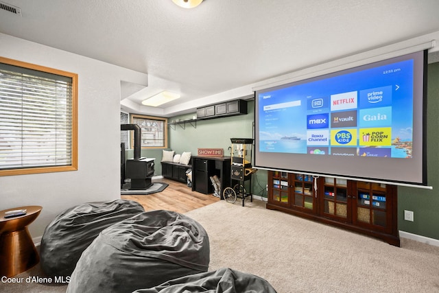 living room with a textured ceiling, light carpet, and a wood stove