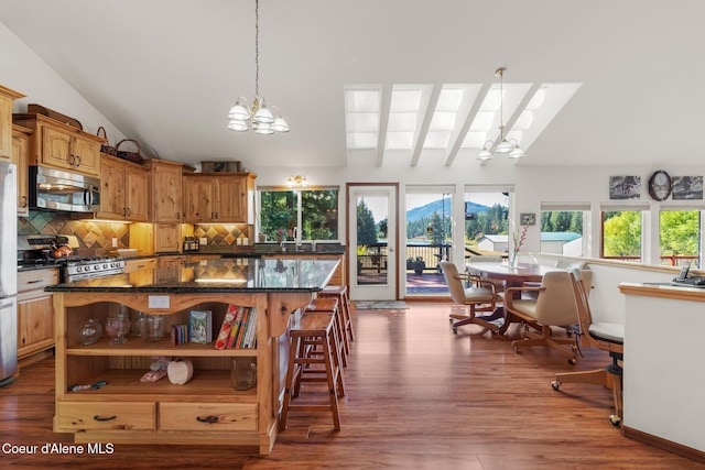 kitchen with a chandelier, hanging light fixtures, dark hardwood / wood-style floors, a kitchen island, and vaulted ceiling with skylight