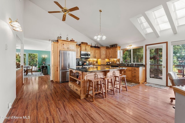 kitchen featuring a breakfast bar area, a center island, light wood-type flooring, stainless steel appliances, and decorative backsplash