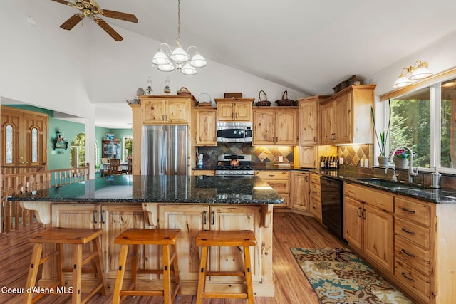 kitchen featuring a kitchen island, appliances with stainless steel finishes, sink, and dark stone countertops