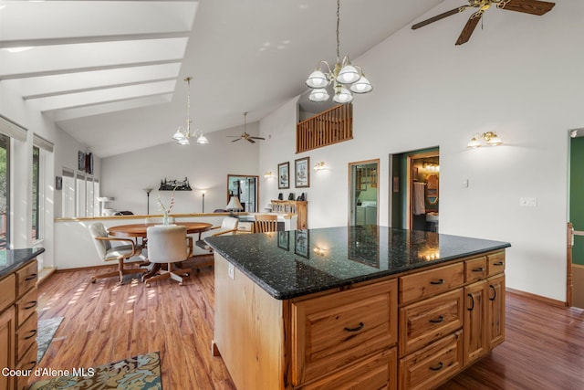 kitchen featuring dark stone counters, hanging light fixtures, a kitchen island, and light wood-type flooring