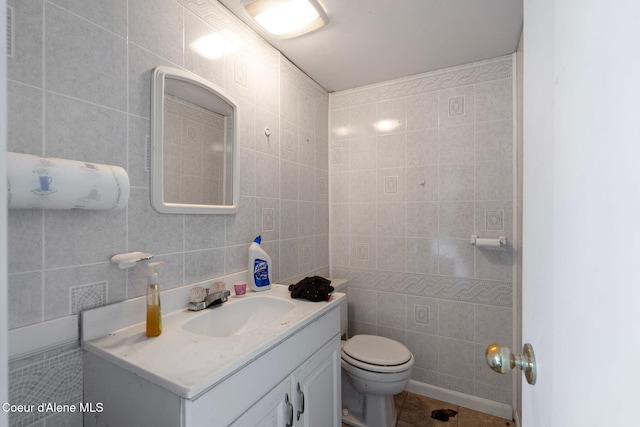 bathroom featuring vanity, toilet, tile patterned flooring, and tile walls