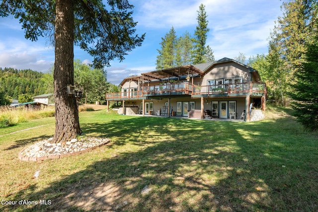 rear view of property with a wooden deck and a lawn