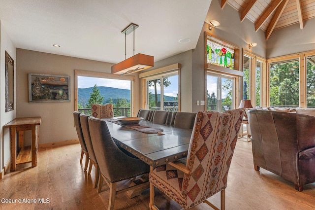 dining area with a mountain view, wood ceiling, vaulted ceiling with beams, and light wood-type flooring