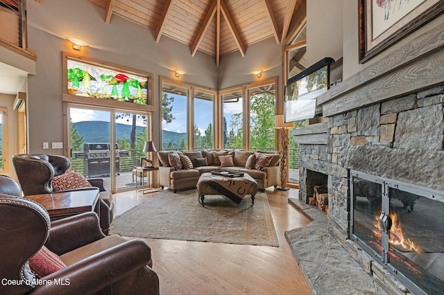 sunroom featuring wood ceiling, a stone fireplace, and vaulted ceiling with beams