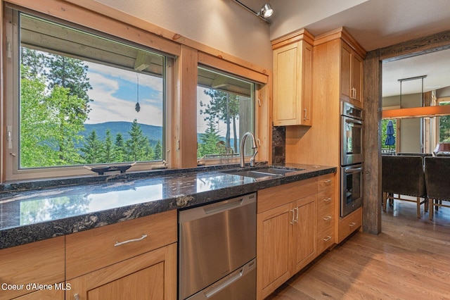 kitchen with sink, stainless steel appliances, light hardwood / wood-style floors, a mountain view, and dark stone counters