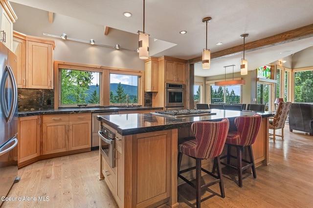 kitchen featuring sink, appliances with stainless steel finishes, tasteful backsplash, a kitchen island, and decorative light fixtures