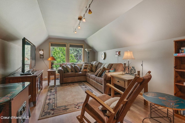 living room with track lighting, light hardwood / wood-style floors, and vaulted ceiling