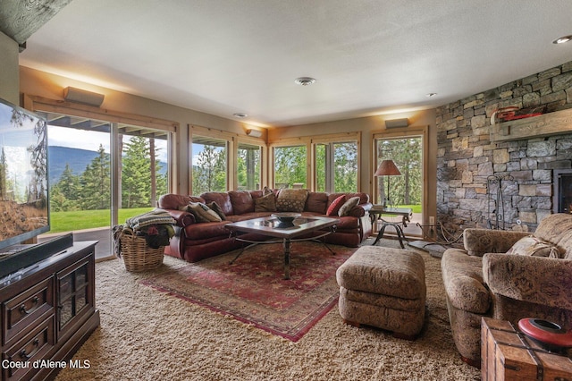 living room featuring carpet flooring, plenty of natural light, a fireplace, and a textured ceiling