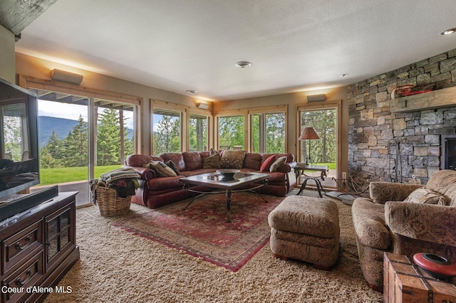 carpeted living room with a fireplace, a textured ceiling, and a wealth of natural light