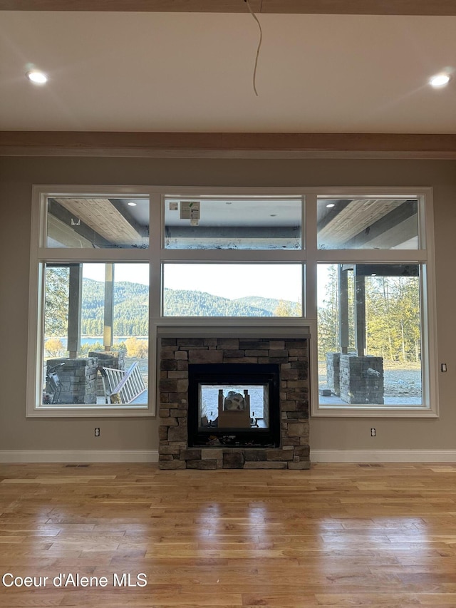 unfurnished living room featuring a stone fireplace and light hardwood / wood-style flooring