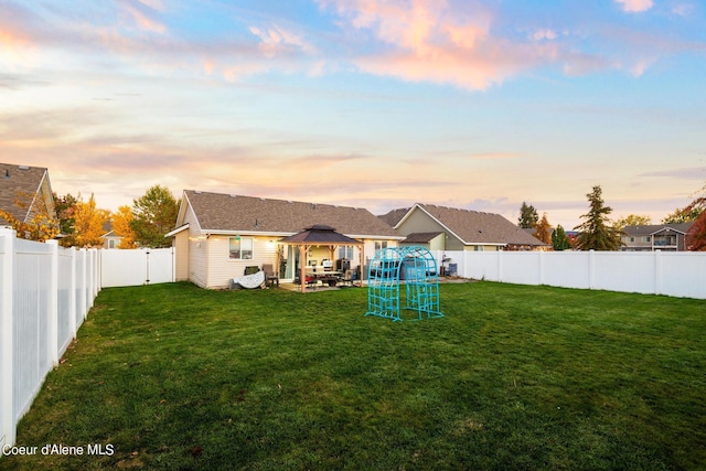 back house at dusk featuring a gazebo, a yard, and a patio