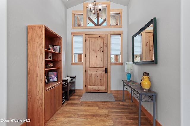 foyer featuring hardwood / wood-style flooring, vaulted ceiling, and a notable chandelier