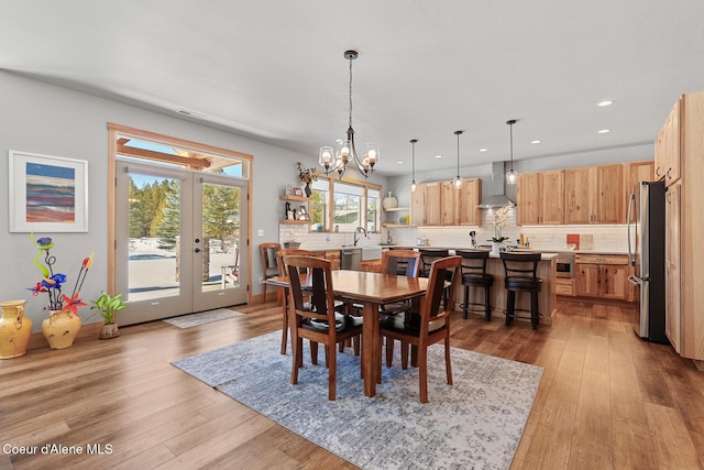 dining room with sink, light hardwood / wood-style flooring, french doors, and a chandelier