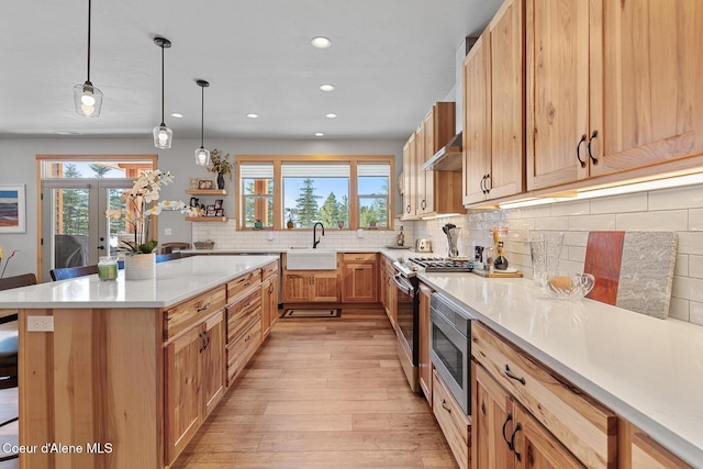 kitchen featuring french doors, a breakfast bar, hanging light fixtures, light wood-type flooring, and stainless steel appliances