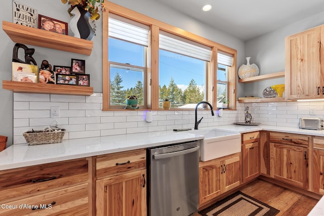 kitchen with sink, backsplash, light stone counters, stainless steel dishwasher, and light wood-type flooring