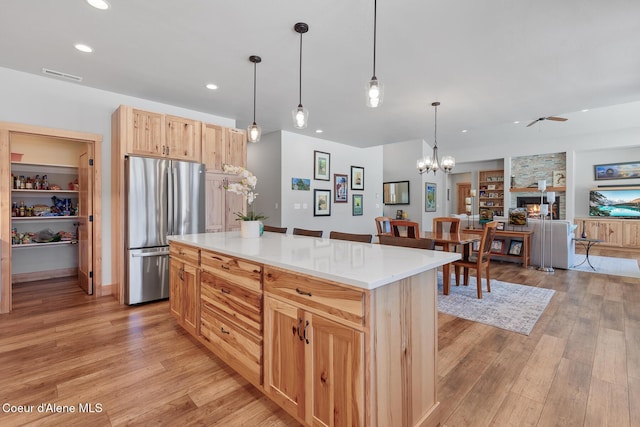 kitchen with a center island, stainless steel fridge, decorative light fixtures, and light hardwood / wood-style floors