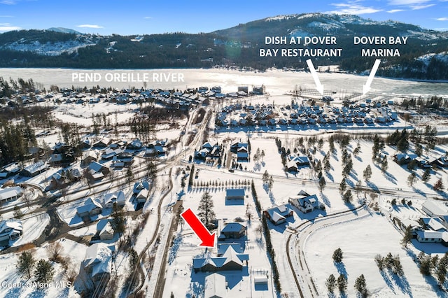 snowy aerial view featuring a water and mountain view