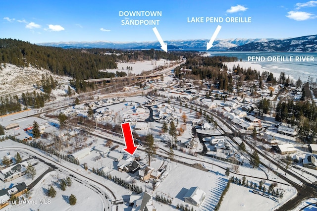 snowy aerial view featuring a water and mountain view