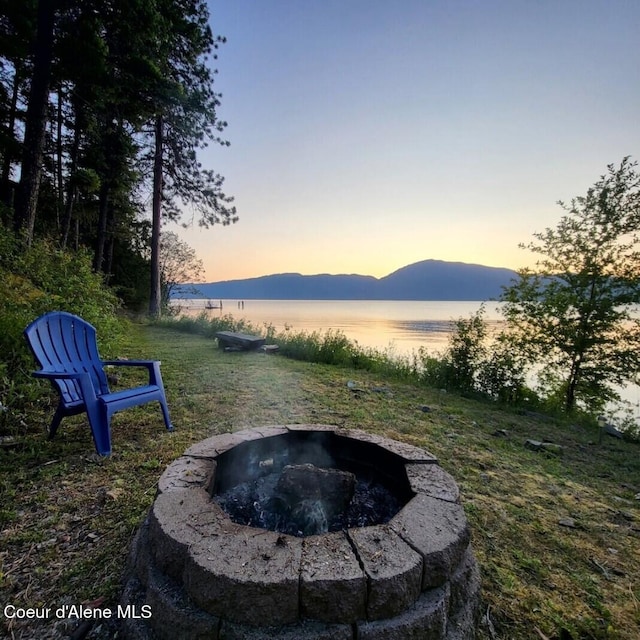 yard at dusk with a water and mountain view and an outdoor fire pit