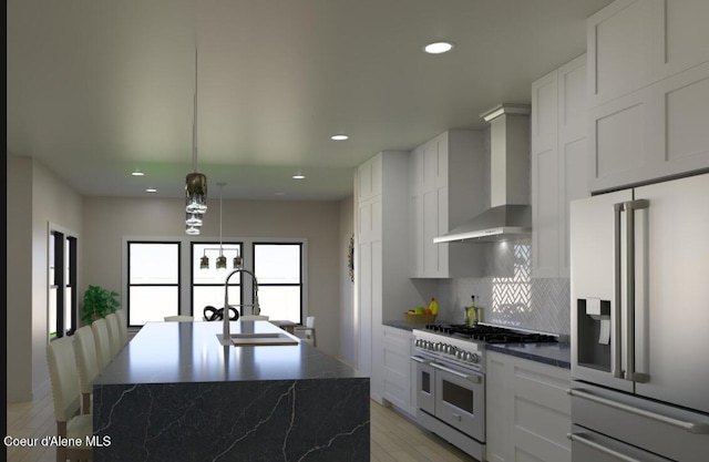 kitchen featuring a sink, stainless steel fridge, wall chimney range hood, range with two ovens, and decorative backsplash