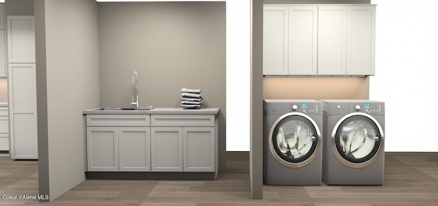 laundry room featuring washing machine and clothes dryer, light wood-style flooring, cabinet space, and a sink