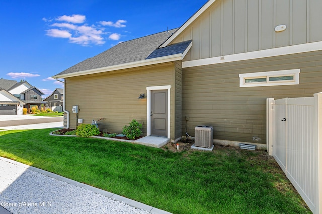 entrance to property featuring central AC unit and a lawn