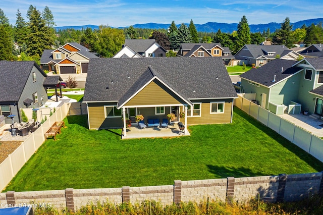 rear view of house featuring a yard, a mountain view, and a patio