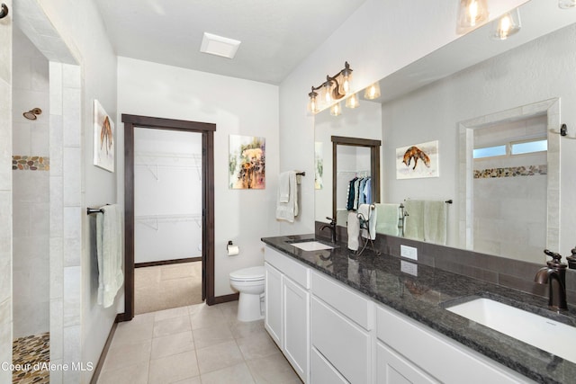 bathroom featuring vanity, tile patterned flooring, toilet, and tiled shower