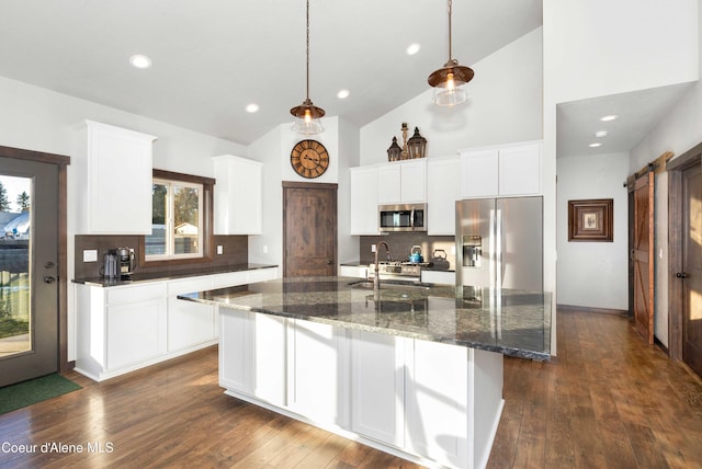 kitchen with sink, hanging light fixtures, appliances with stainless steel finishes, a barn door, and white cabinets