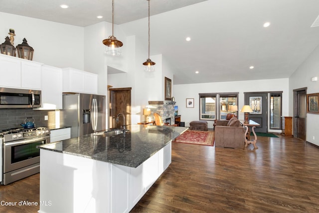 kitchen with pendant lighting, sink, appliances with stainless steel finishes, white cabinetry, and dark stone countertops