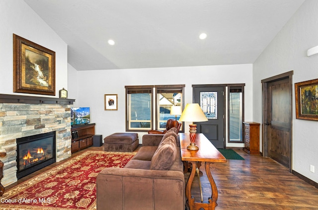 living room featuring dark wood-type flooring, a stone fireplace, and vaulted ceiling