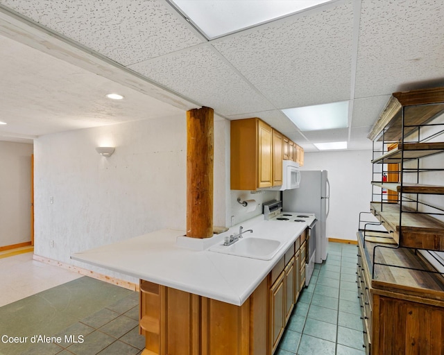 kitchen featuring sink, white appliances, a paneled ceiling, and light tile patterned flooring