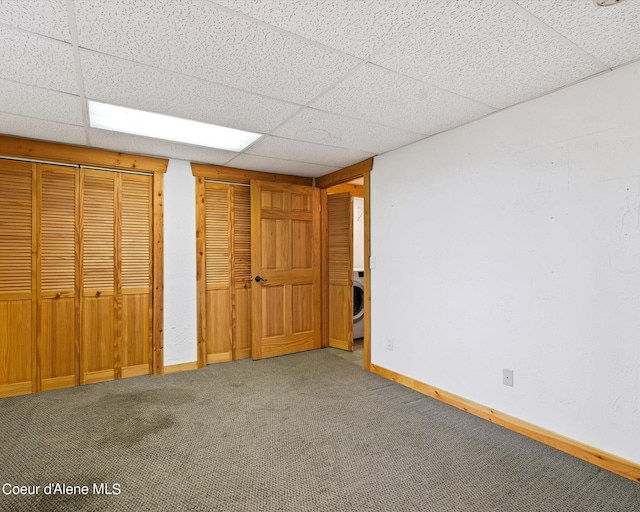 unfurnished bedroom featuring multiple closets, carpet flooring, washer / clothes dryer, and a drop ceiling