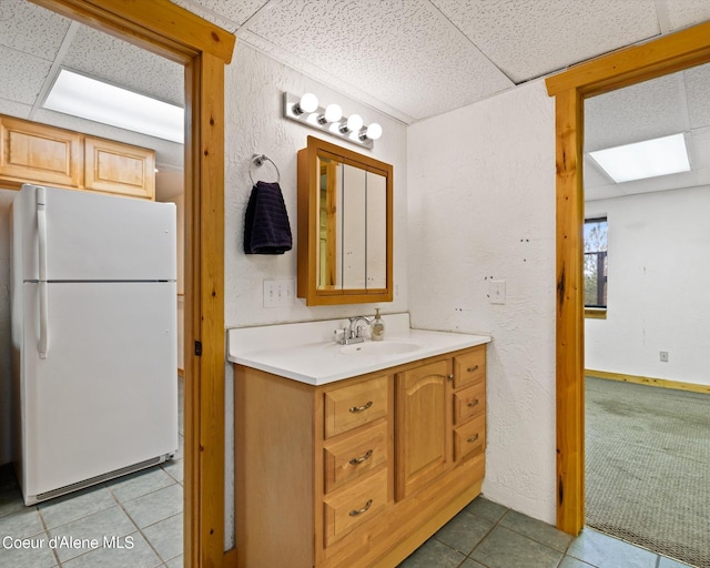 bathroom featuring tile patterned flooring, vanity, and a paneled ceiling